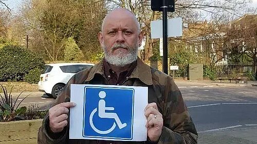 Terry Stacy holding blue badge sign